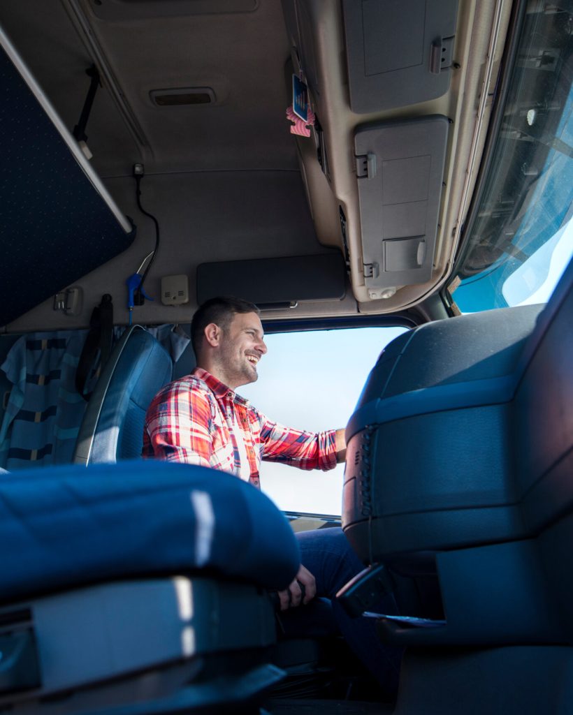 Professional truck driver steering and driving vehicle on highway. Inside view of trucker driving long vehicle. Transportation and distribution services.