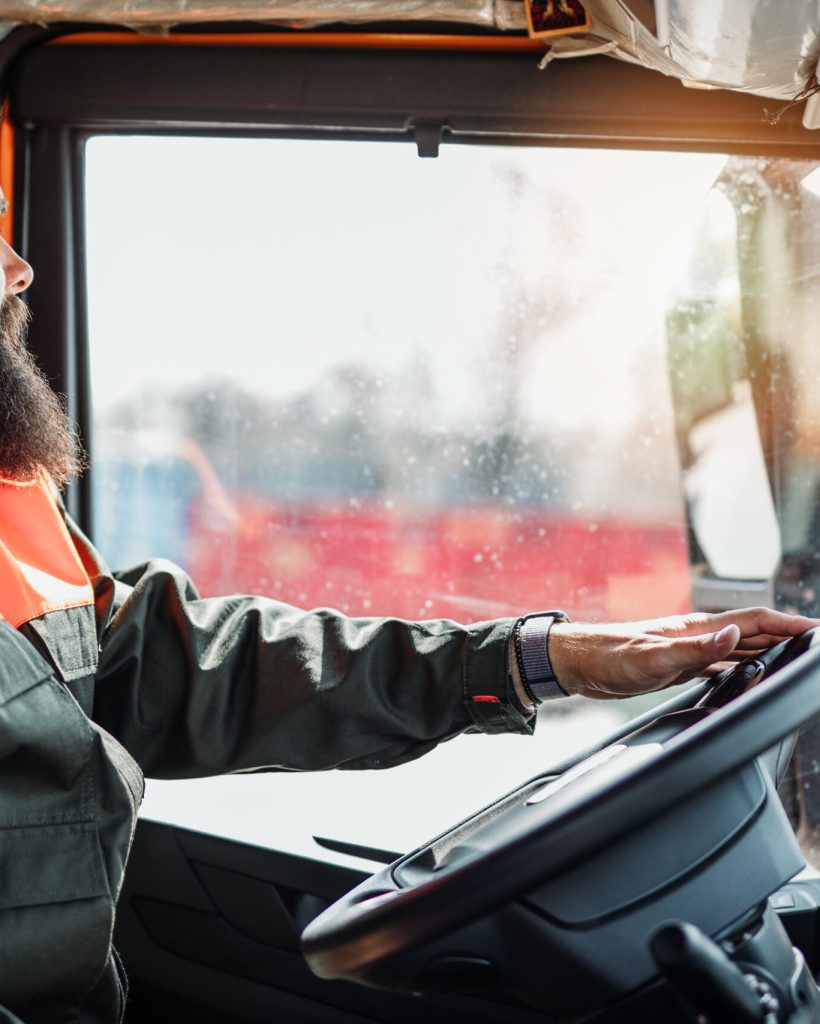 Young garbage removal worker driving a waste truck